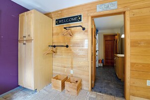 Una puerta de madera con un cartel que dice 'WELCOME', un perchero y un pequeño cofre de madera.