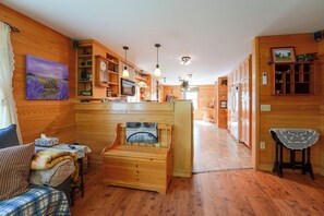 A cozy interior with wooden walls, a fireplace, a dining area, and a kitchen.
