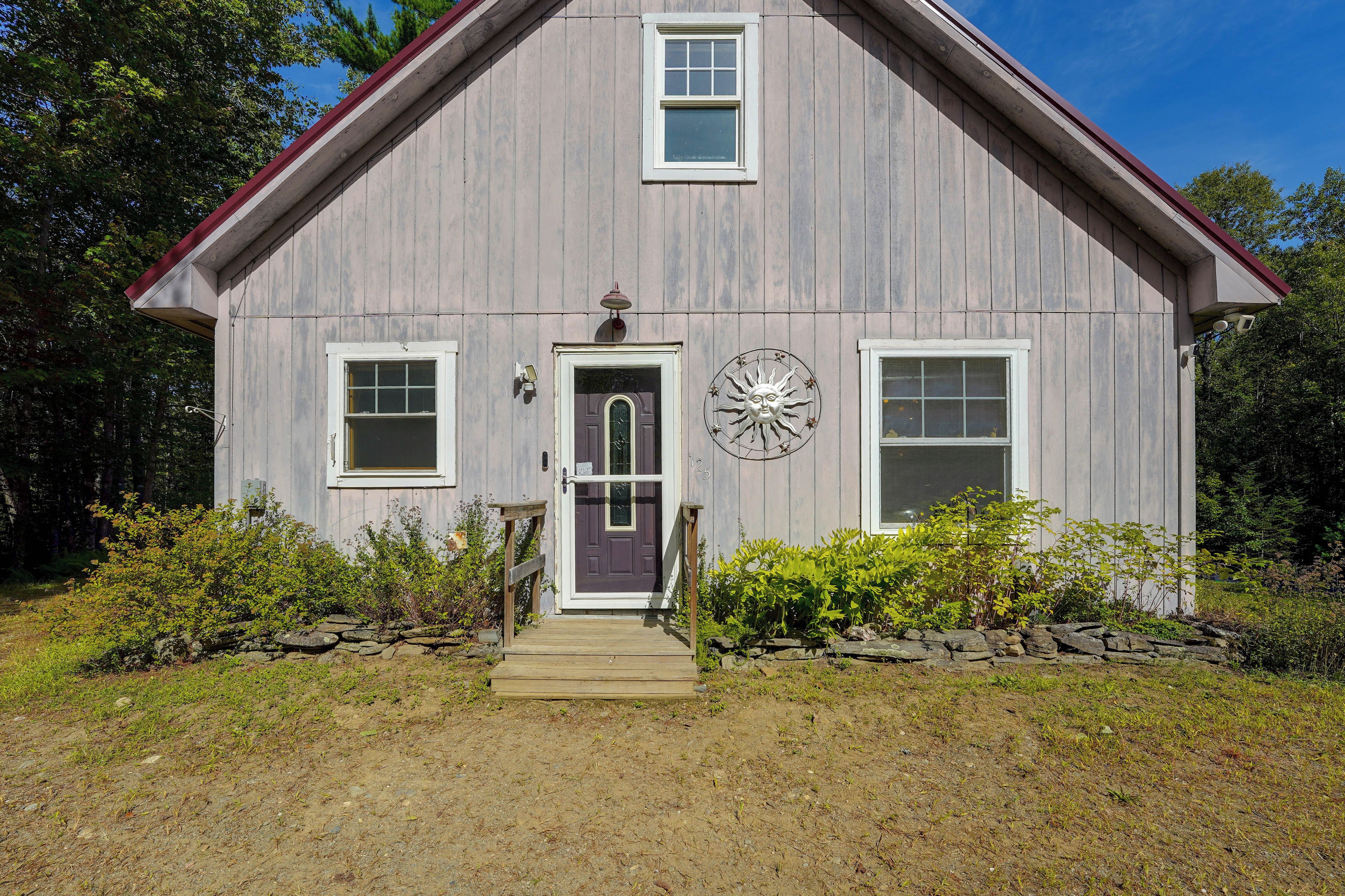 A two-story wooden house with a front porch, a mailbox, and a decorative sun emblem.