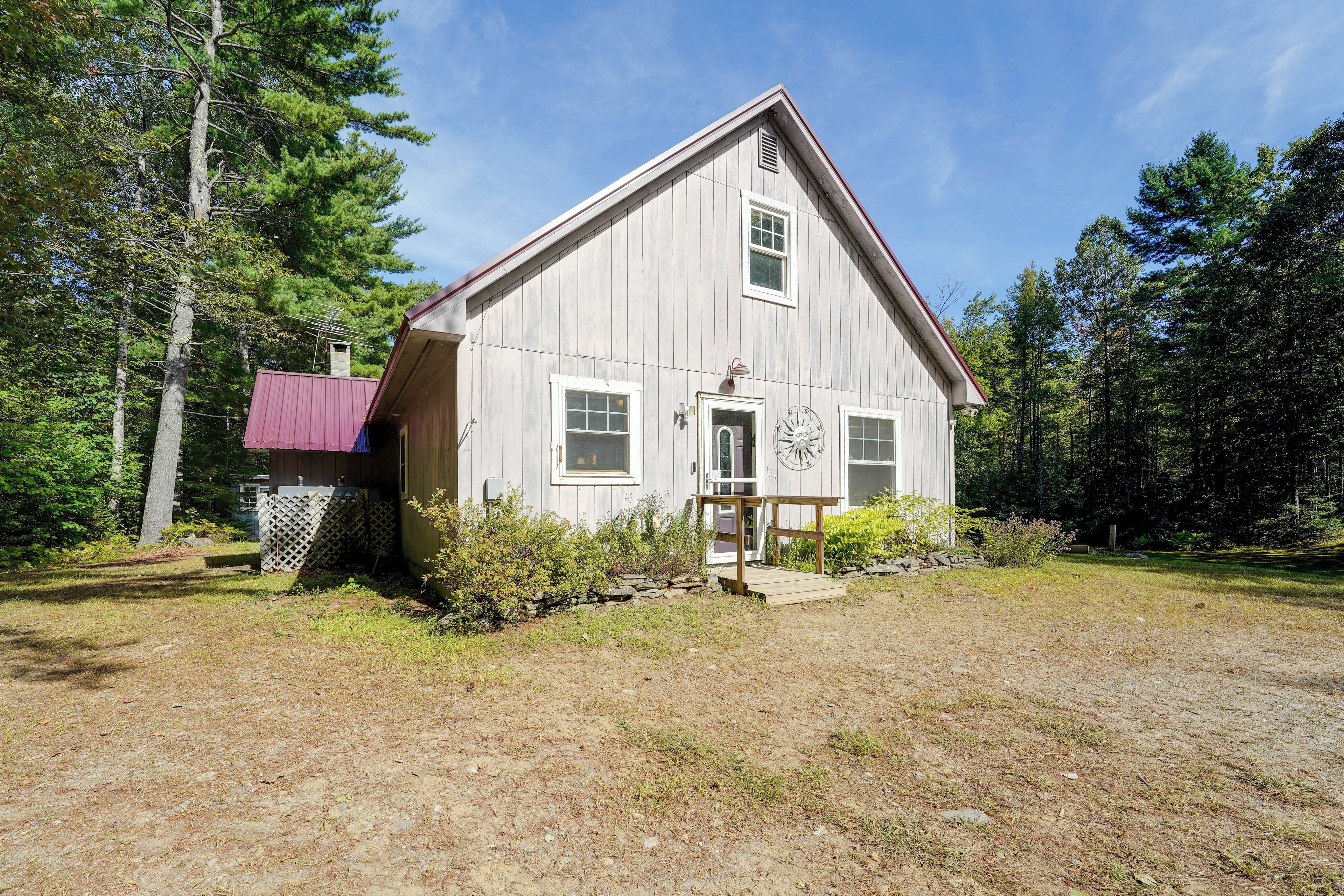 A single-story wooden house with a gabled roof, a front porch, and a small deck.