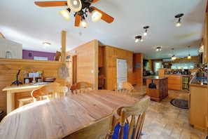 Un interior de madera con una mesa de comedor, sillas, una zona de cocina y un ventilador de techo.