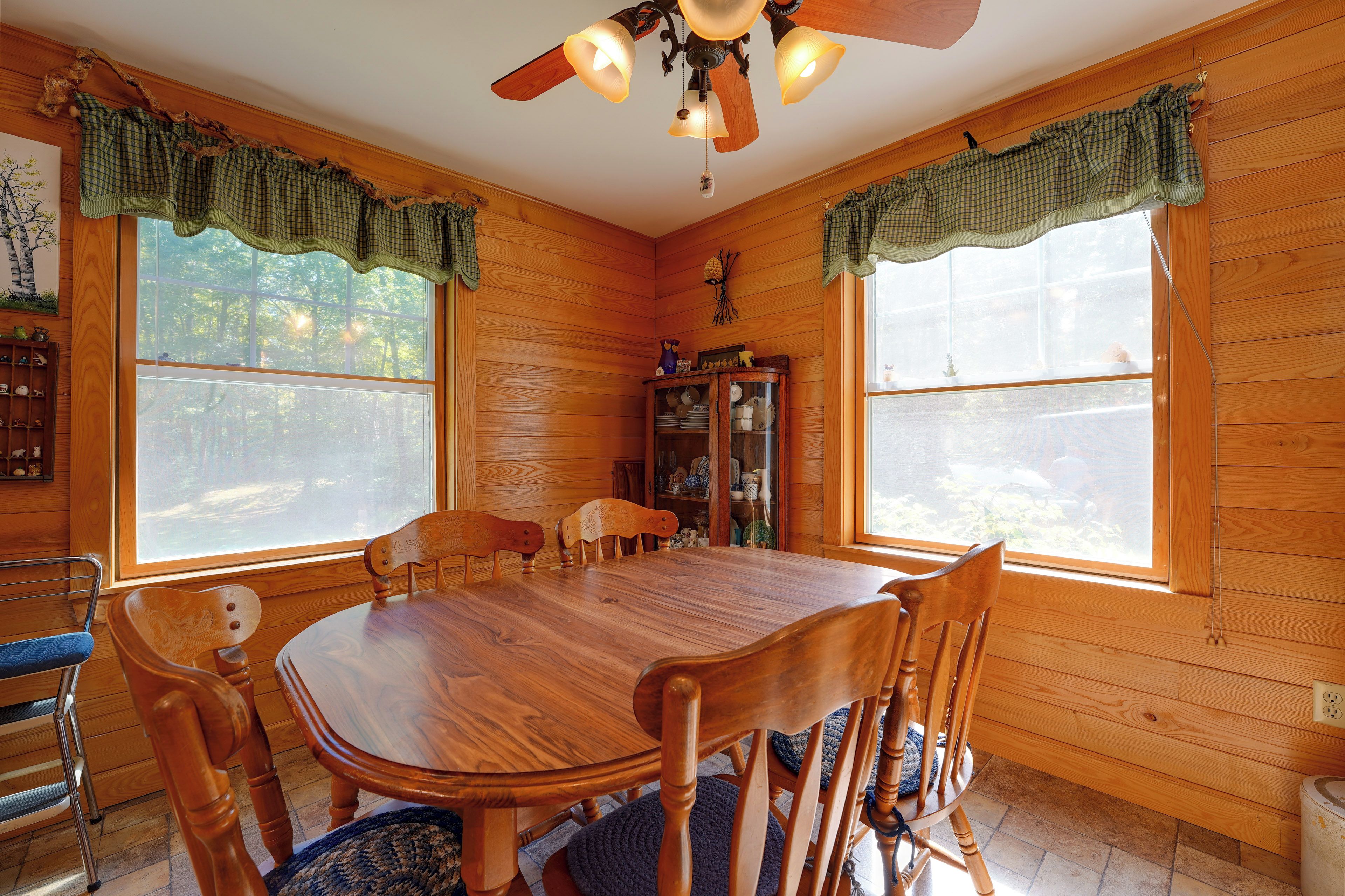 A wooden interior with a dining table, chairs, and a cabinet.