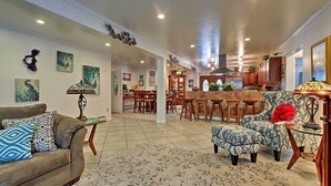 A spacious living area with a sofa, ottoman, and patterned rug. There is a dining area with a wooden table and chairs, and a kitchen in the background. - Expansive Getaway ~ 2 Miles to Mendenhall Glacier! (Juneau)