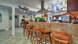 A modern kitchen with a central island, bar stools, and stainless steel appliances. - Expansive Getaway ~ 2 Miles to Mendenhall Glacier! (Juneau)