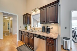 A modern kitchen with dark wood cabinets, stainless steel dishwasher, and a granite countertop.