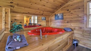 A wooden cabin interior with a red hot tub, a small plant, and a towel on the counter. - Gatlinburg Cabin w/ Pool Table & Hot Tub! (Sevierville)