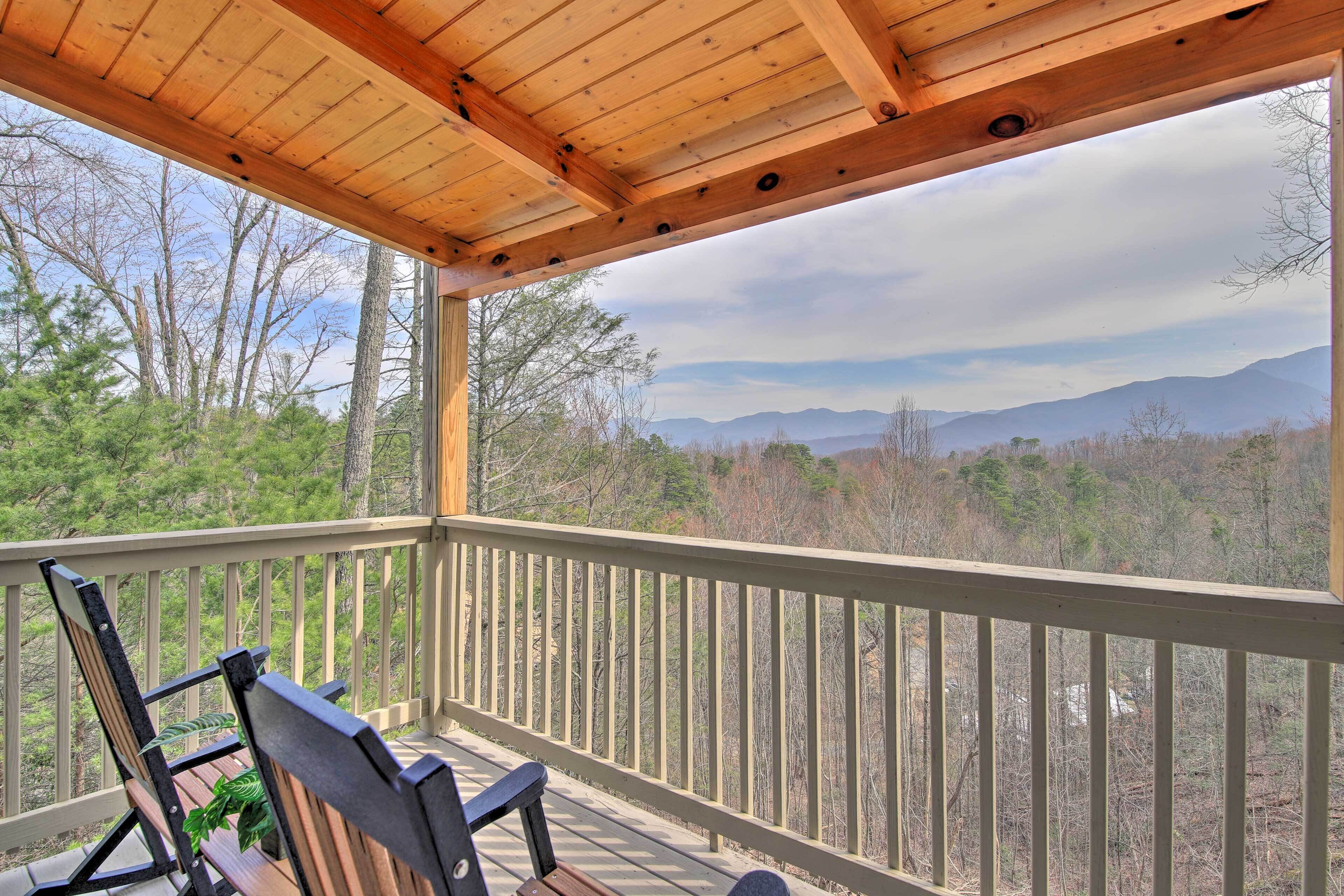 A wooden deck with a view of mountains and trees.