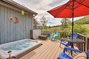 Une terrasse dotée d’un jacuzzi, de mobilier d’extérieur et d’un parasol rouge.