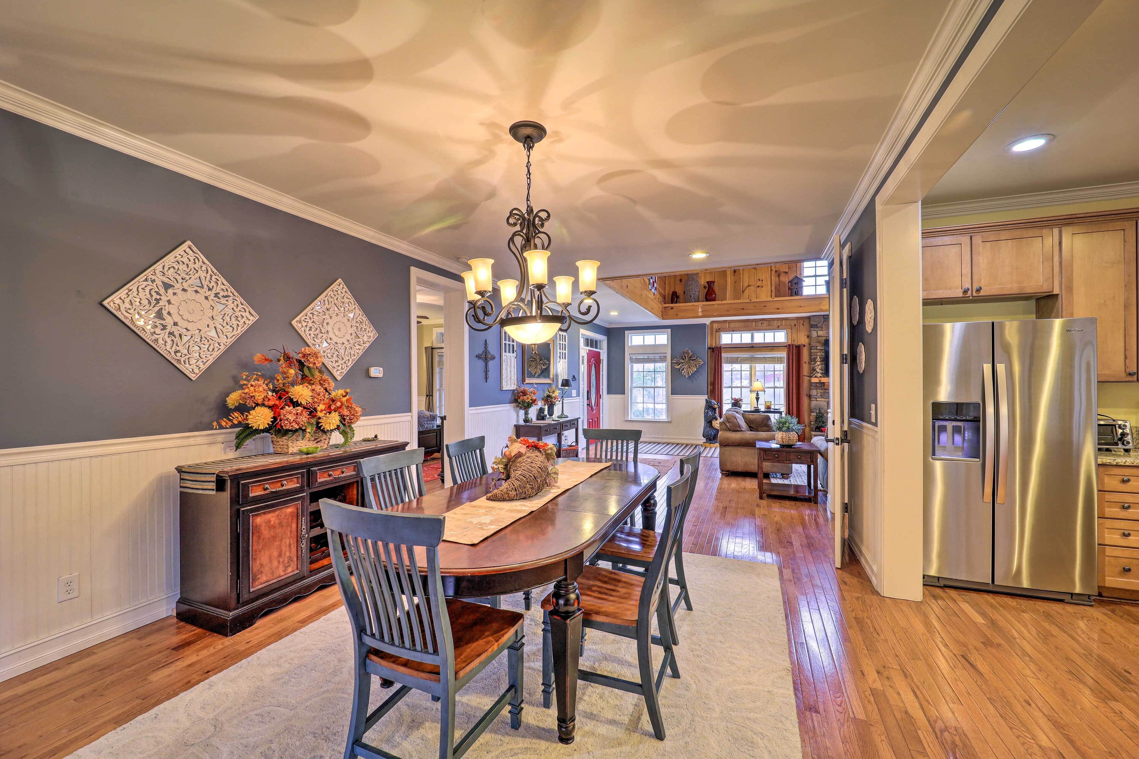 A spacious kitchen with a central island, stainless steel refrigerator, and a chandelier.
