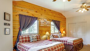 A room with two beds, wooden paneling, a ceiling fan, and a door. - Duck Creek Village Cabin Near National Forest! (Duck Creek Village)