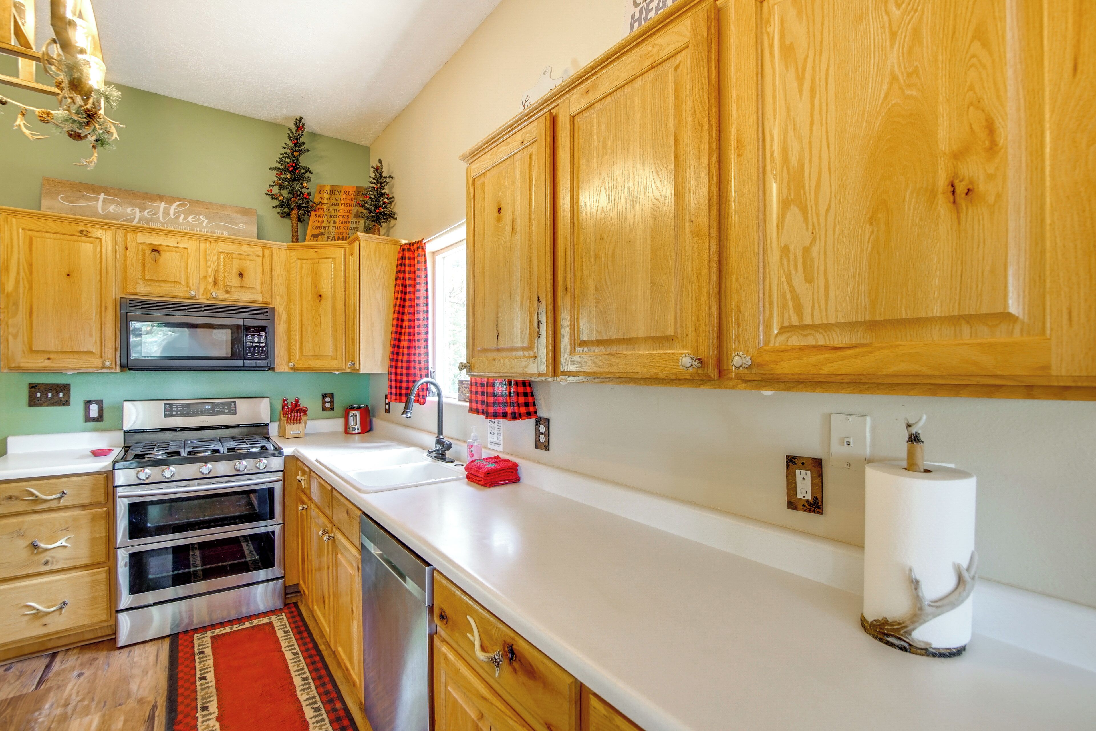A kitchen with wooden cabinets, a stainless steel stove, a microwave, and a red checkered towel.