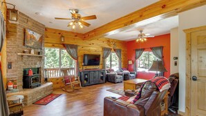 A log cabin interior with a fireplace, wooden furniture, and a television. - Duck Creek Village Cabin Near National Forest! (Duck Creek Village)