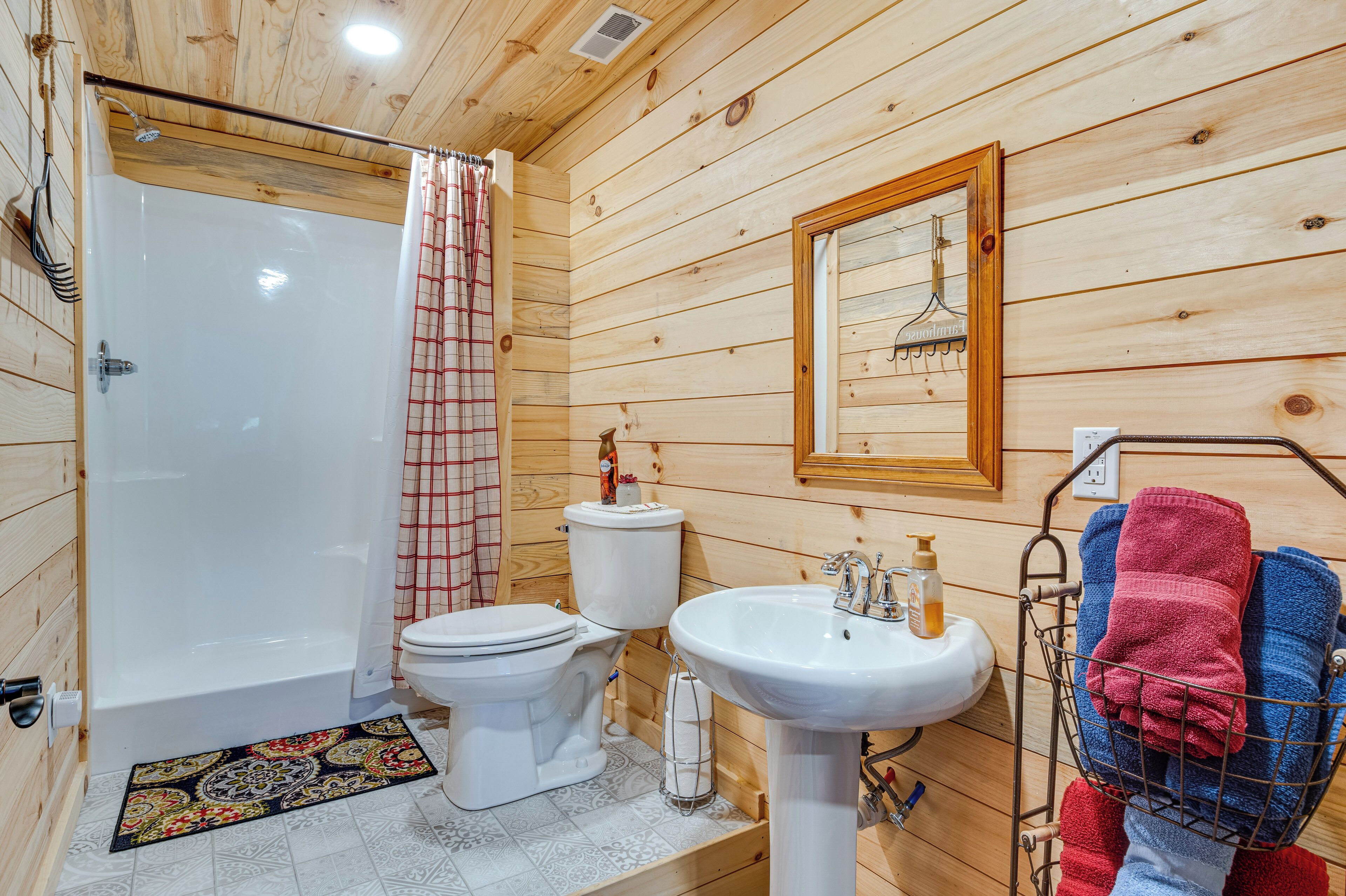 A wooden-paneled bathroom with a bathtub, toilet, sink, and a towel rack with towels.