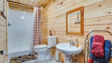 A wooden-paneled bathroom with a bathtub, toilet, sink, and a towel rack with towels.