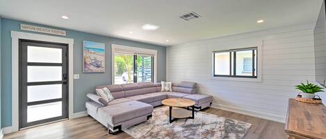 A modern living room with a sectional sofa, a round coffee table, and a large window.