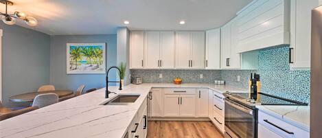 A modern kitchen with white cabinets, a large island, and a tiled backsplash.