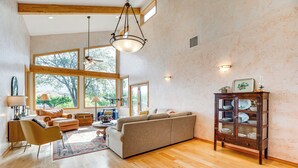 A spacious living room with a large sofa, wooden flooring, and a dining area with a cabinet. - 'mesa View House' w/ Hot Tub: Walk to Winery! (Palisade)