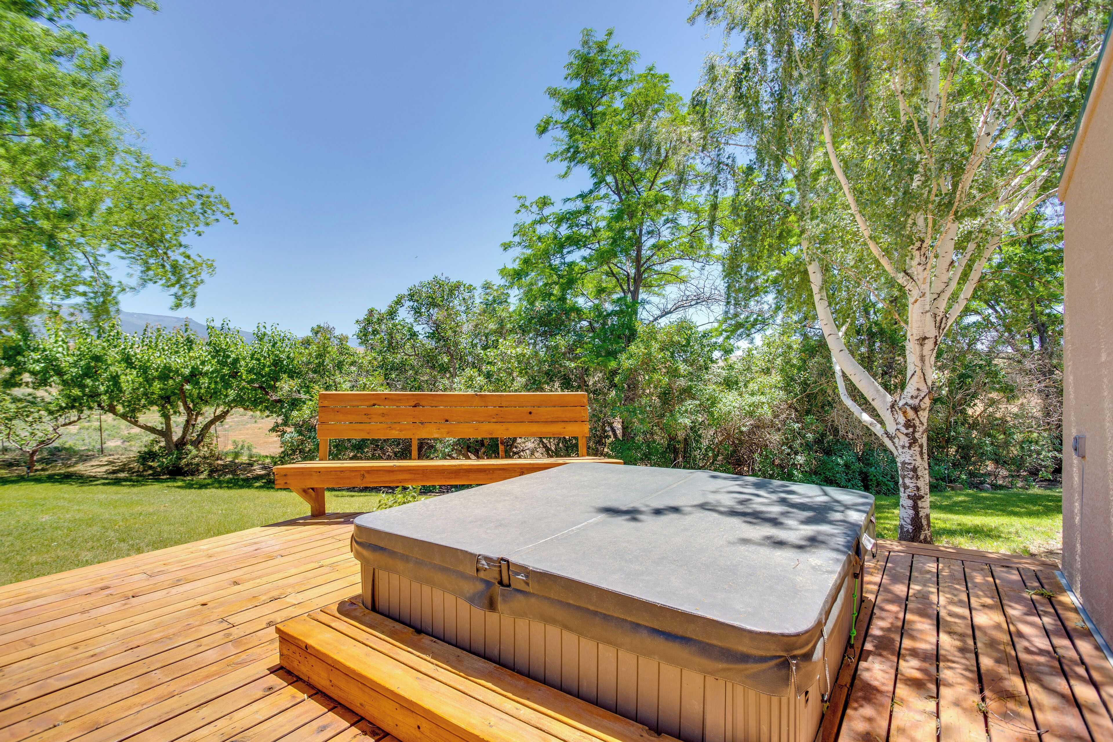 A wooden deck with a hot tub and a bench.
