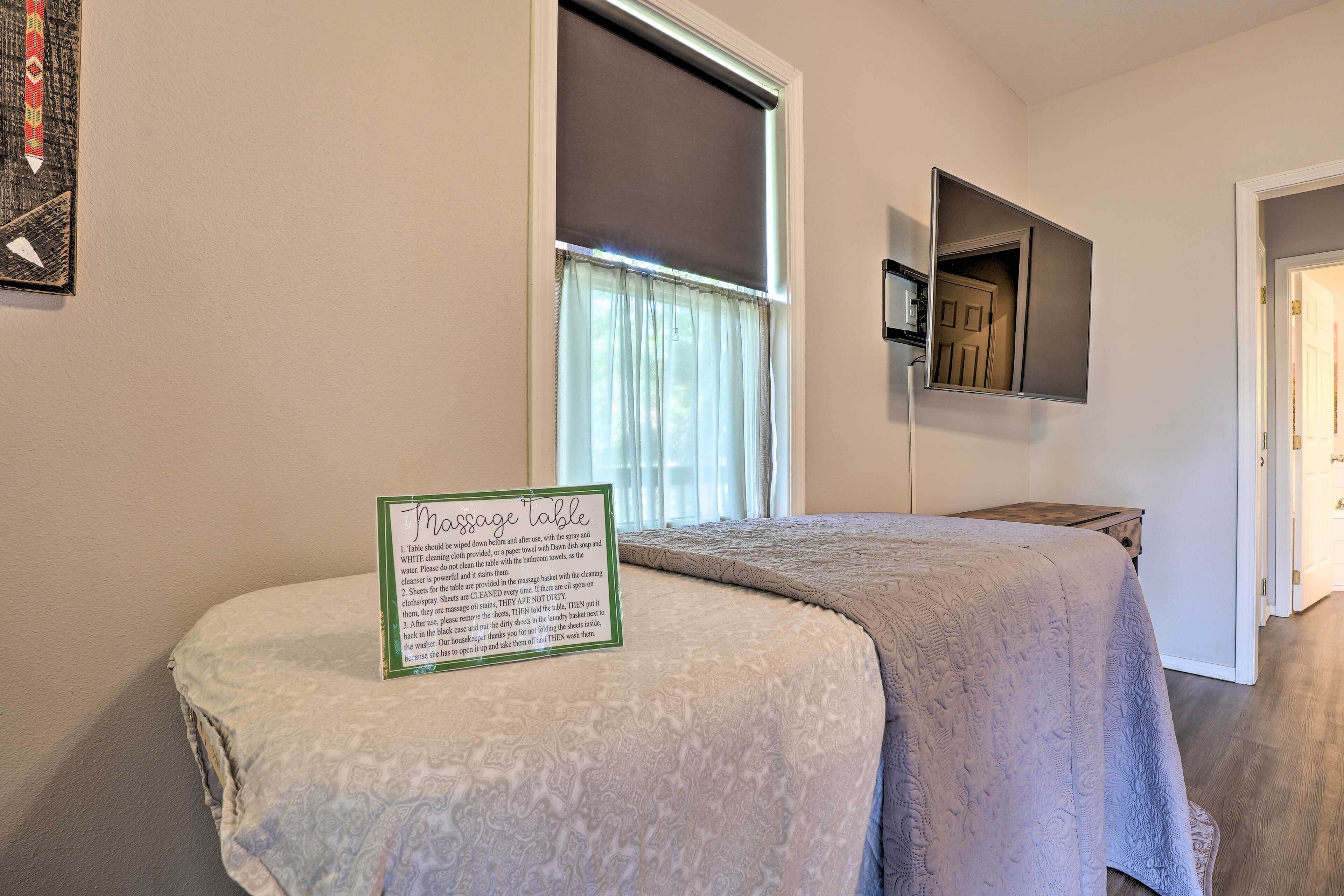 A massage table with a sign detailing table care instructions, a window with curtains, and a door in the background.