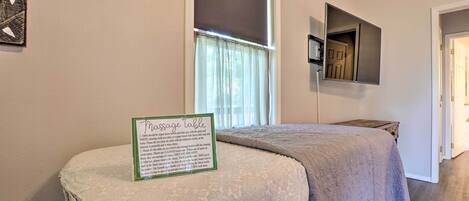 A massage table with a sign detailing table care instructions, a window with curtains, and a door in the background.