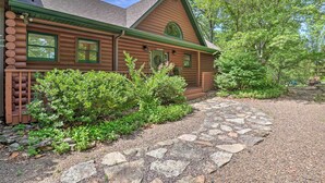 A log cabin with a stone pathway leading to the entrance, surrounded by lush greenery. - Beaver Lake Home w/ Game Room, Boat Slip & Views! (Eureka Springs)