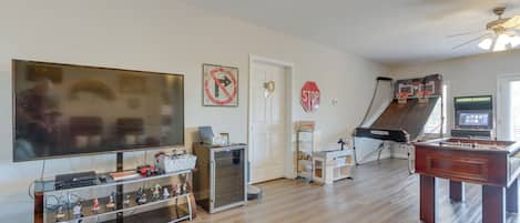 A living room with a foosball table, a TV, and a ceiling fan.