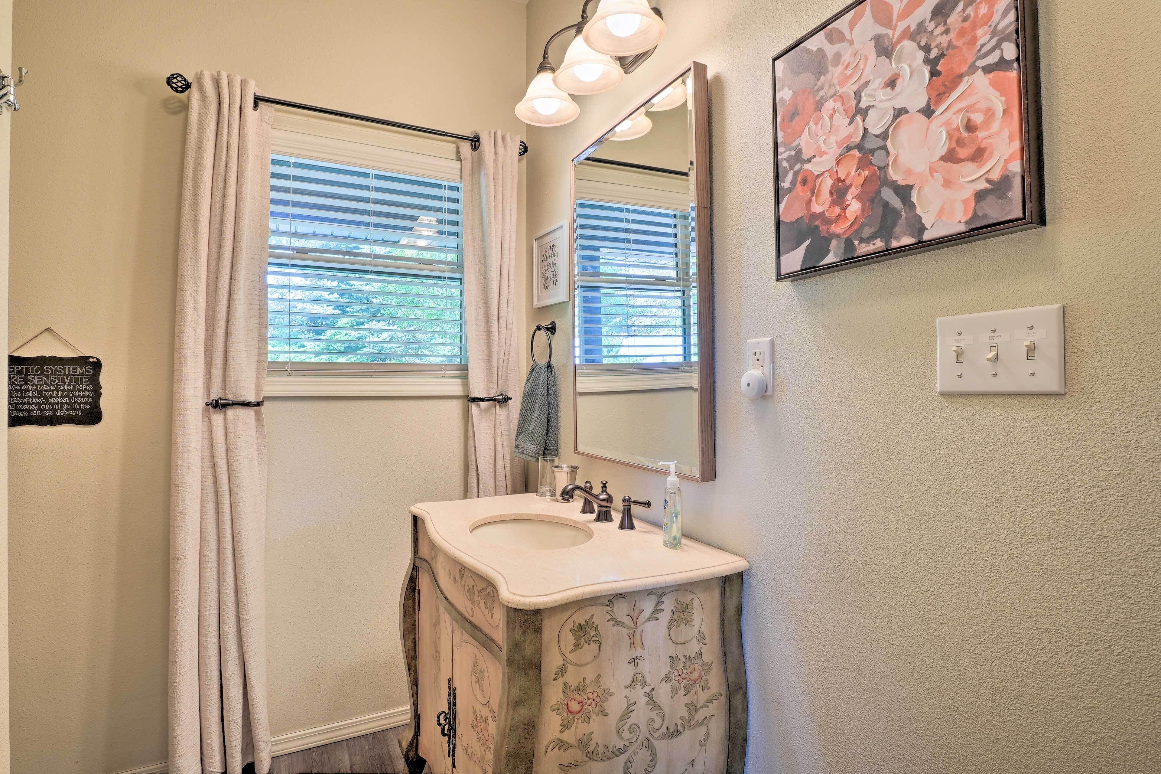 A bathroom with a sink, mirror, and window with blinds.