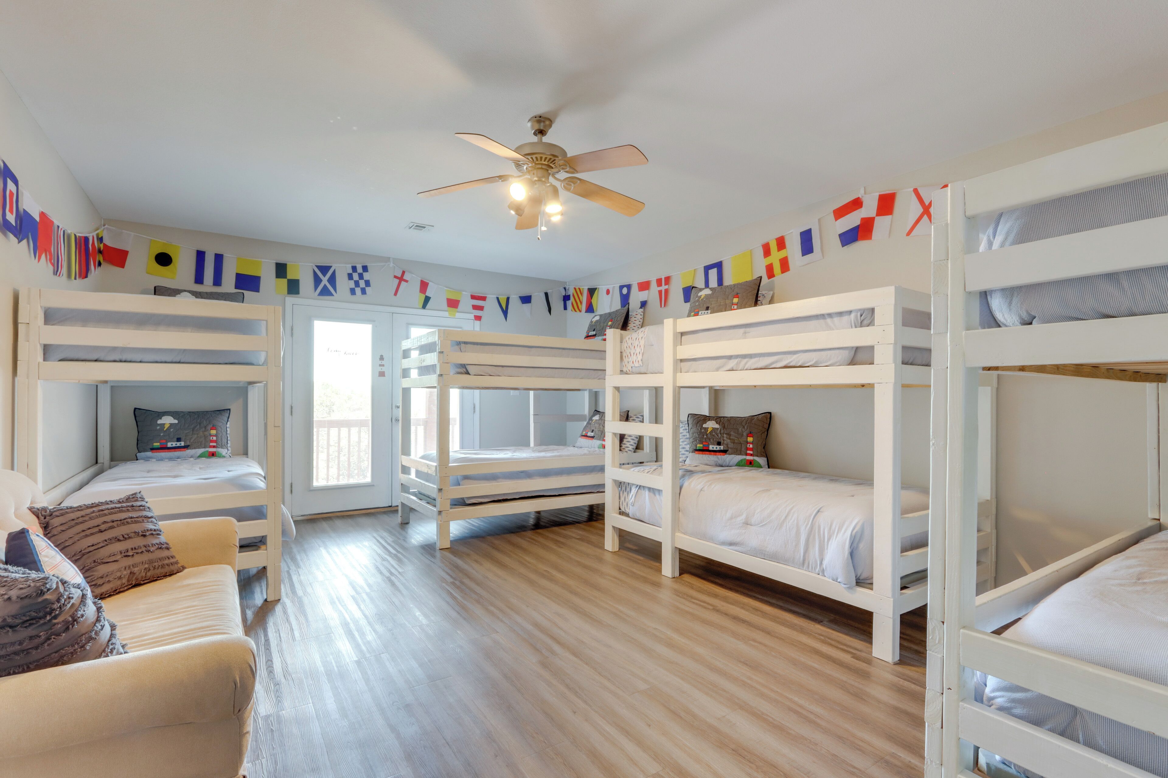 A room with bunk beds, a ceiling fan, and a view of the outdoors.