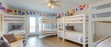 A room with bunk beds, a ceiling fan, and a view of the outdoors.
