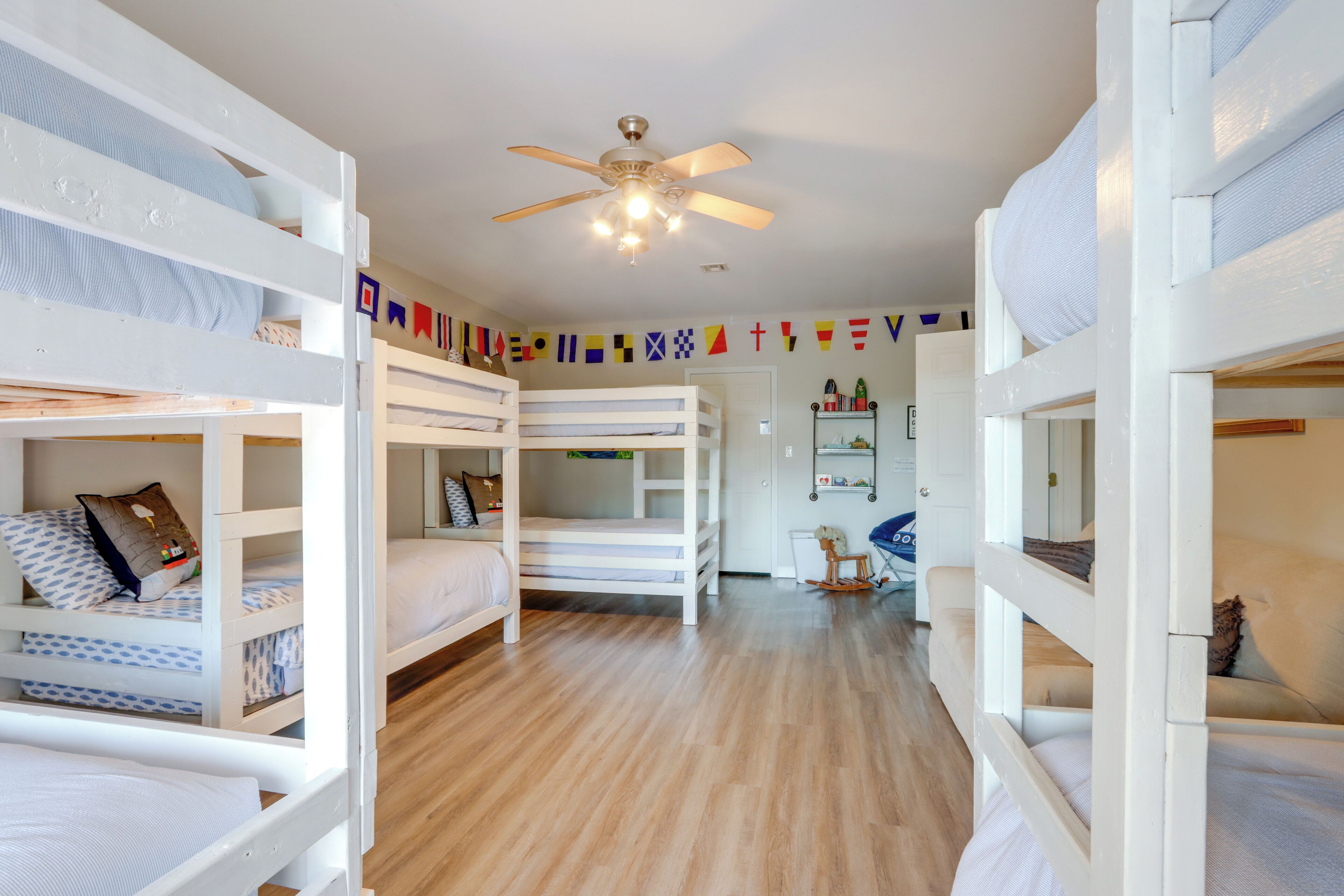 A room with bunk beds, a ceiling fan, and a wooden floor.
