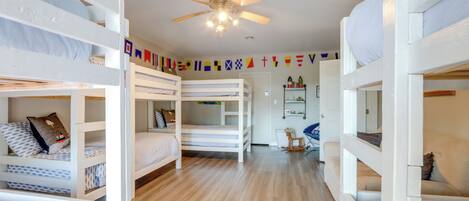 A room with bunk beds, a ceiling fan, and a wooden floor.