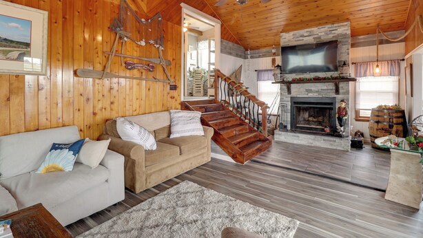 Ein gemütliches Blockhaus-Interieur mit Holzausstattung, Kamin, Treppe und einer Couch.