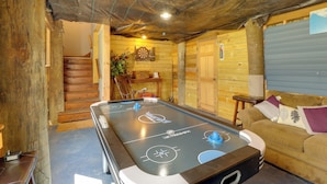 Ein Holzinterieur mit einem Shuffleboard-Tisch, einer Treppe und einem Sofa.