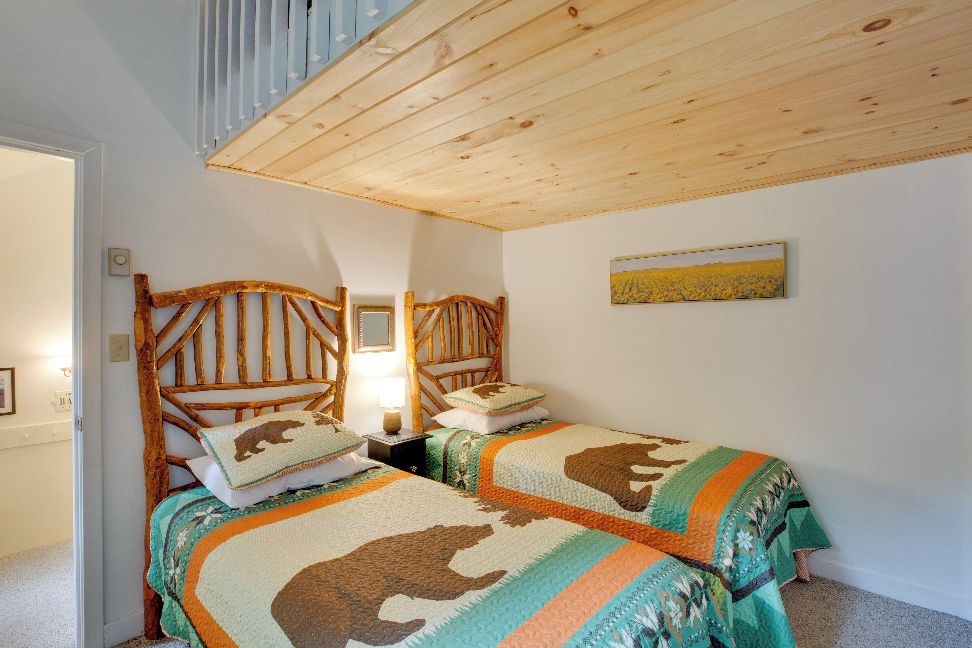 Una habitación con dos camas literas de madera, un cuadro en la pared y un techo con vigas a la vista.