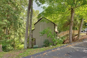 Un petit bâtiment d’un seul étage, doté d’un toit en pente, entouré d’arbres denses et agrémenté d’une terrasse en bois.