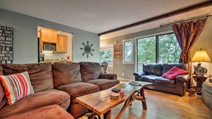A living room with a brown leather couch, a wooden coffee table, and a kitchen in the background.