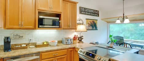 A kitchen with wooden cabinets, a built-in microwave, a coffee maker, a toaster, and a stove.