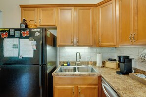 A kitchen with wooden cabinets, a stainless steel refrigerator, a sink, and a coffee maker.
