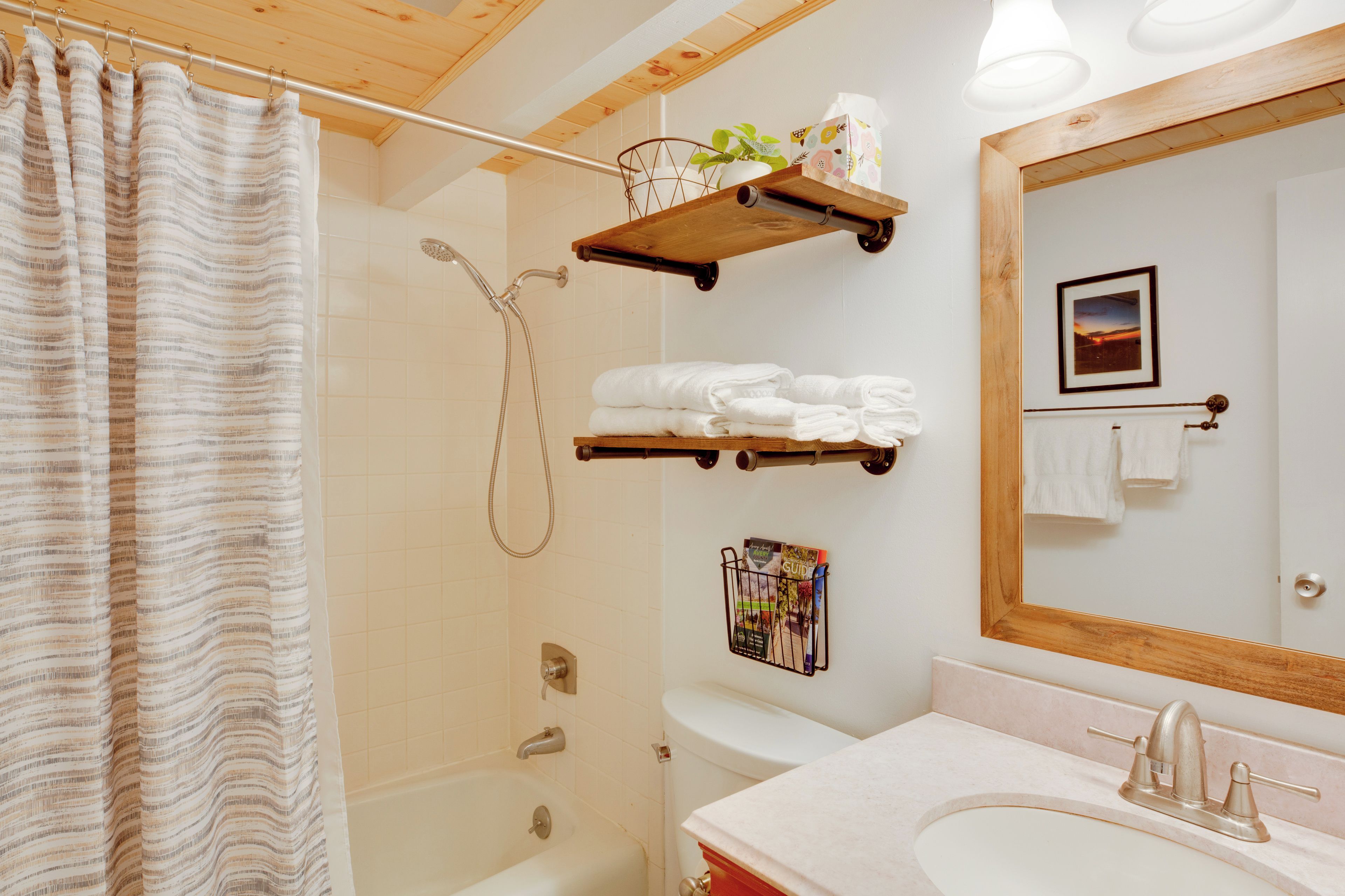 A bathroom with a shower, a toilet, a sink, and a mirror.