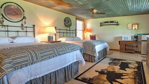 A room with two beds, a ceiling fan, a wall-mounted lamp, a mirror, a microwave, and a dresser. - Delightful Carmine Studio on Rocking Horse Farm! (Carmine)
