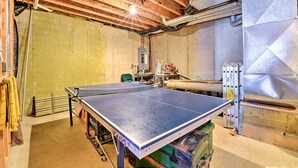 A ping pong table in a room with wooden beams on the ceiling and a large metallic radiator.