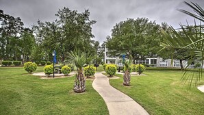 A well-maintained garden with a central pathway leading to a building with a white facade and multiple windows. - Golfer's Paradise: Myrtle Beach Condo w/ Pool! (Myrtle Beach)