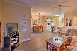 A living room with a flat-screen TV, wooden coffee table, and a plush armchair. - Golfer's Paradise: Myrtle Beach Condo w/ Pool! (Myrtle Beach)