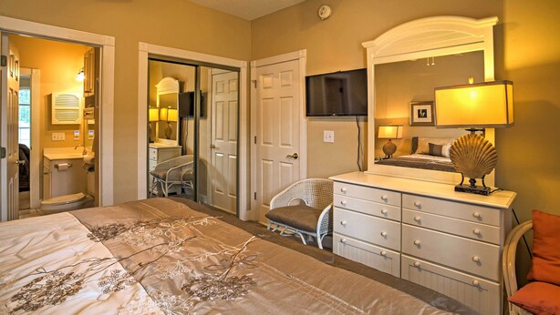 A bedroom with a bed, dresser, chair, and a television on the wall. - Golfer's Paradise: Myrtle Beach Condo w/ Pool! (Myrtle Beach)