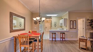 A dining area with a wooden table and chairs, a chandelier, and a kitchen in the background. - Golfer's Paradise: Myrtle Beach Condo w/ Pool! (Myrtle Beach)