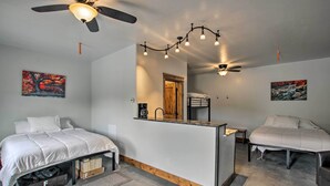 A bedroom with two beds, a small kitchenette, and a ceiling fan. - Modern Lava Hot Springs Studio, Walk to Pools (Lava Hot Springs)