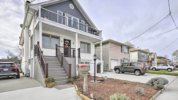 A two-story residential building with a front porch, a mailbox, and a small garden area. - Island Park Couple's Escape ~ 1 Mi to Beach! (Island Park)