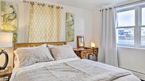 A bedroom with a bed, bedside table, lamp, and a window with curtains. - Island Park Couple's Escape ~ 1 Mi to Beach! (Island Park)