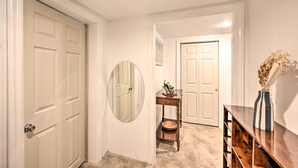 A hallway with white doors, a round mirror, a small wooden table with a vase, and a wooden bench. - Island Park Couple's Escape ~ 1 Mi to Beach! (Island Park)
