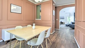 A dining area with a wooden table and white chairs, a framed picture on the wall, and a view into another room. - Modern Durham Retreat w/ Private Yard & Patio (Durham)